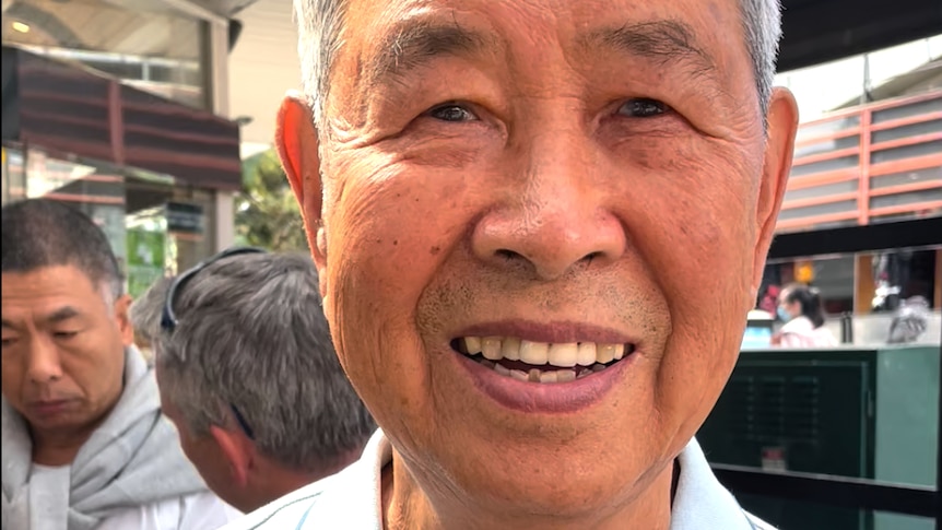 An elderly Chinese man looking to the camera and smiling.