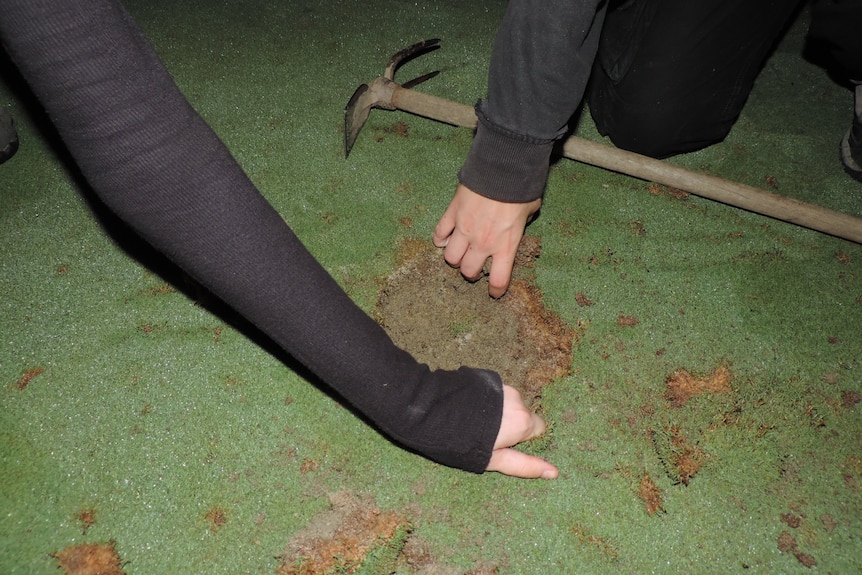 Two hands are seen filling a golf course hole with cement.