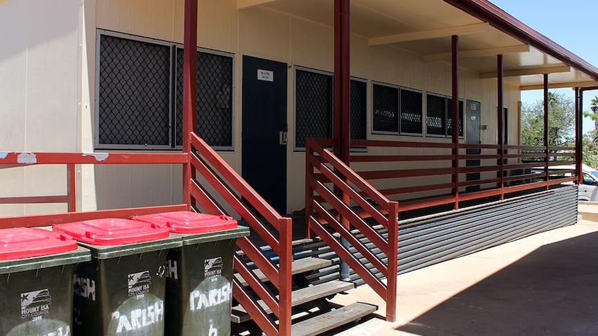 A cream-coloured demountable building with timber steps, railings and decking.