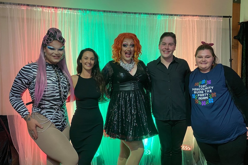 Two drag queens, Ellawarra and Roxee Horror posing with three students, including Sam Hollingshead. 