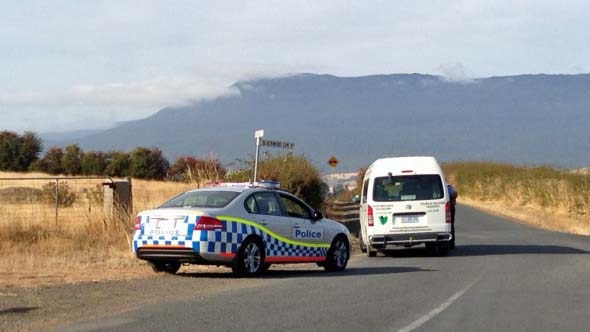A Tasmanian police vehicle blocks a road in Tasmania as police search for a couple who shot at police.