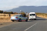 A Tasmanian police vehicle blocks a road in Tasmania as police search for a couple who shot at police.