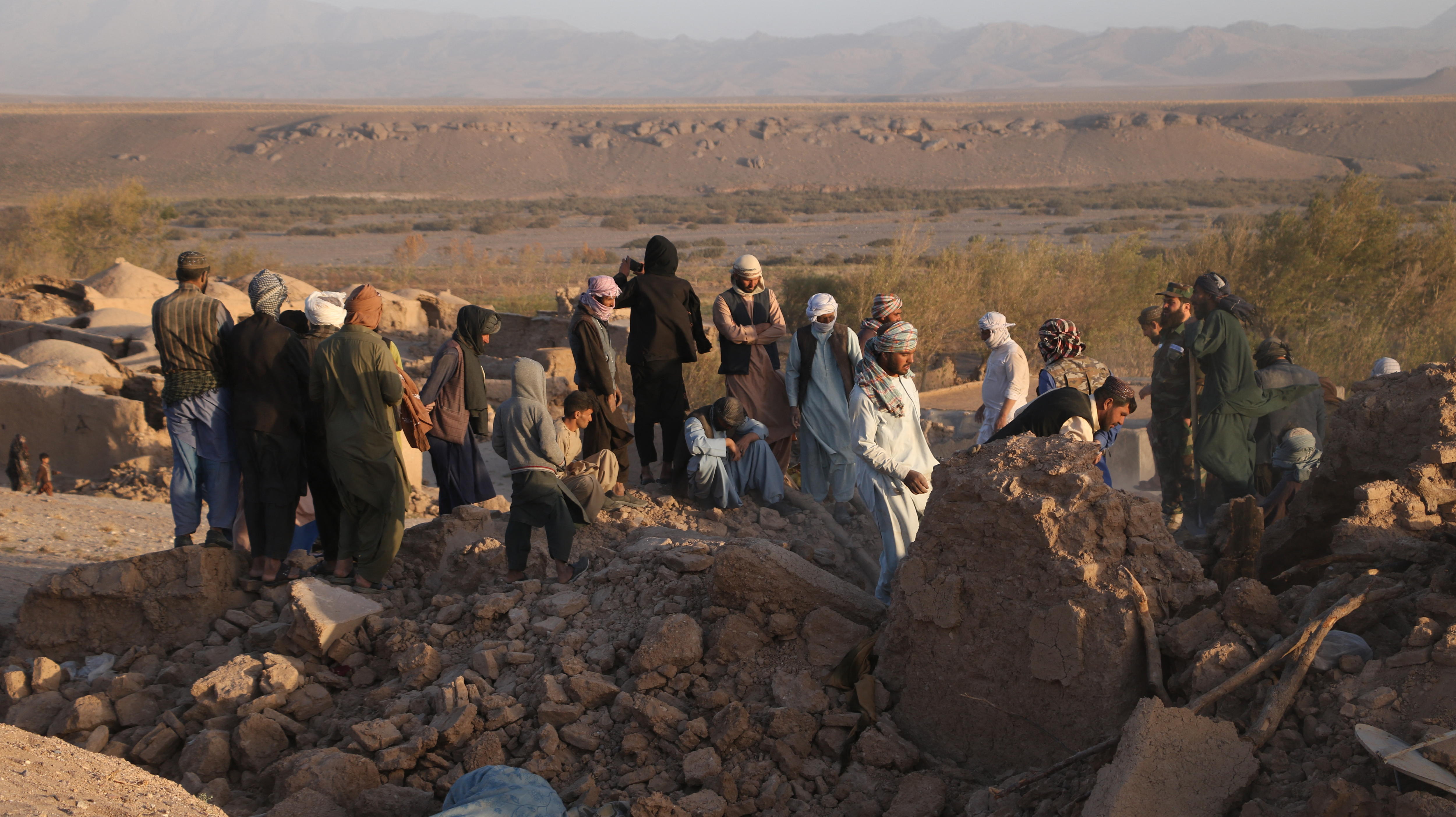 a group of men stand around on rubble
