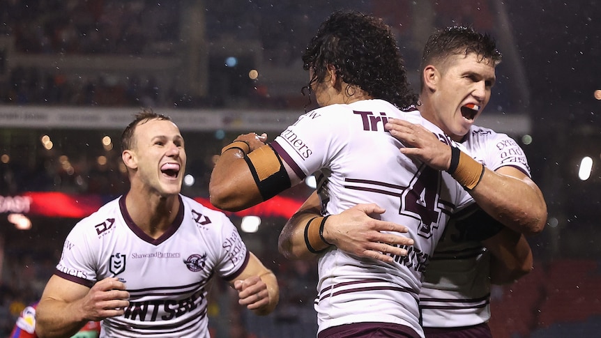 Manly Sea Eagles' Daly Cherry-Evans smiles wide as he runs to hug Morgan Harper, who is being hugged by Reuben Garrick.