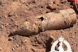 An old bomb is seen lying atop dirt at a construction site.