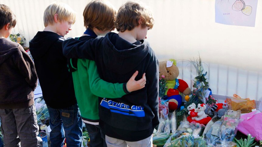 Children from 't Stekske school comfort one another as they lay flowers in front of their school building in Lommel