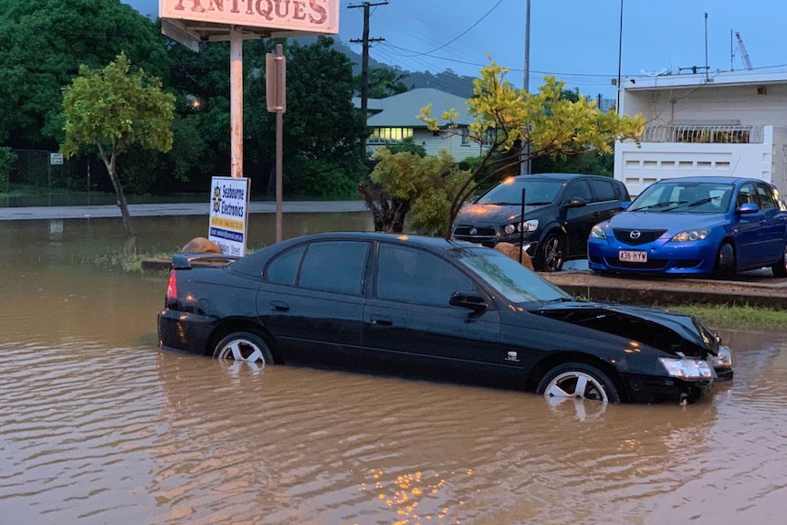 A damaged car sits in floodwaters/