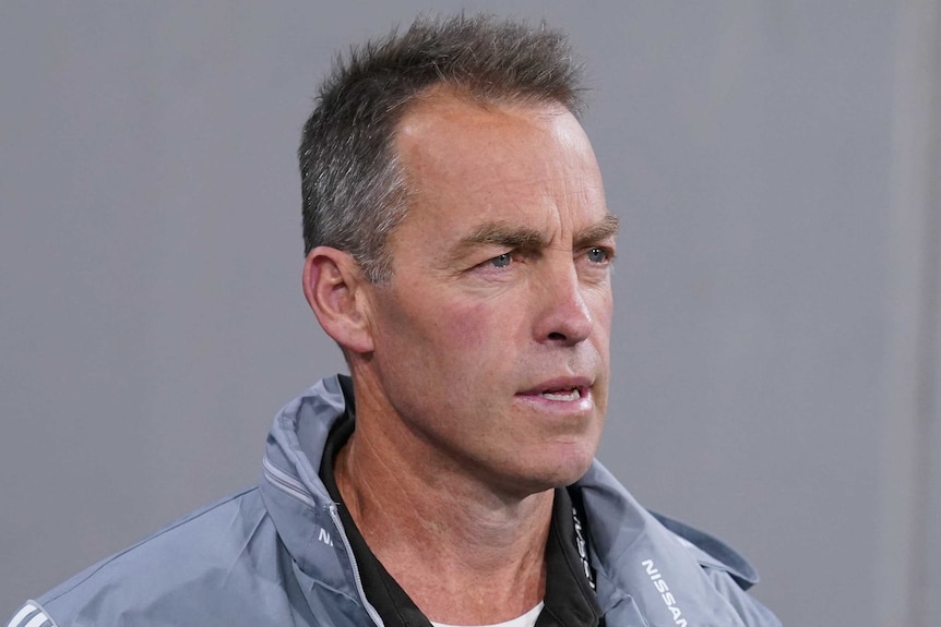 Alastair Clarkson wears a gray jacket and looks pensive