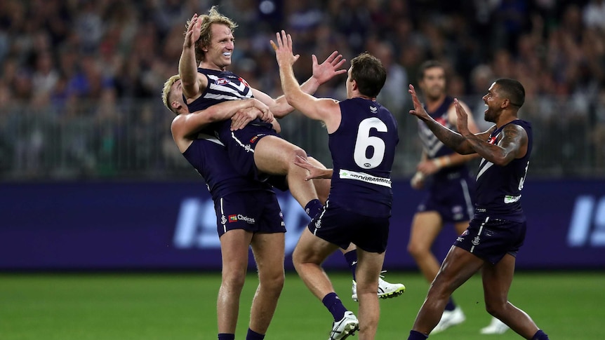 David Mundy smiles and spreads his arms out wide as he is held in the air by Dockers teammate Luke Ryan.