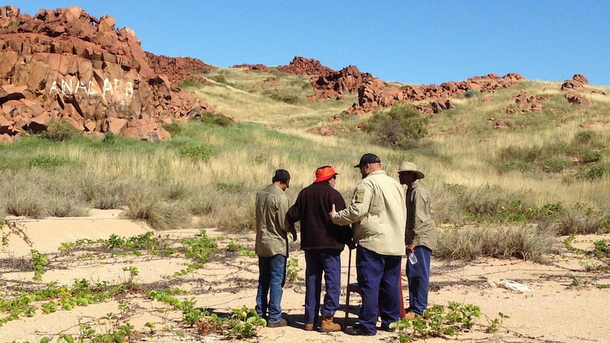 A vandal's sign in white is clearly seen on rocks at Burrup as Aboriginal elders and rangers gather to discuss it.