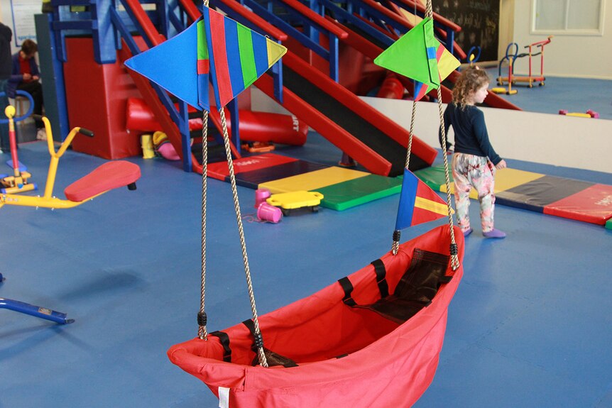 A red material boat hangs on ropes from the ceiling.