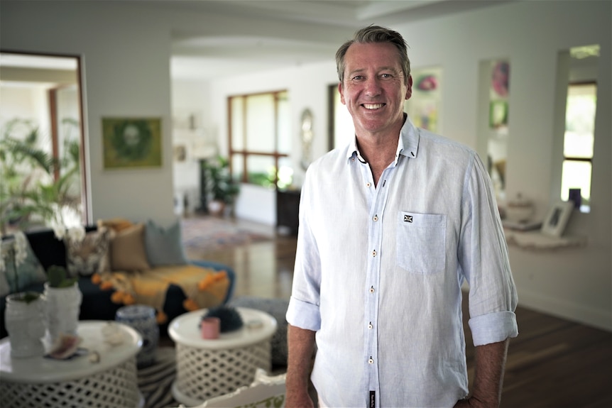 Portrait of a man wearing a light blue button up shirtn standing in a loungeroom