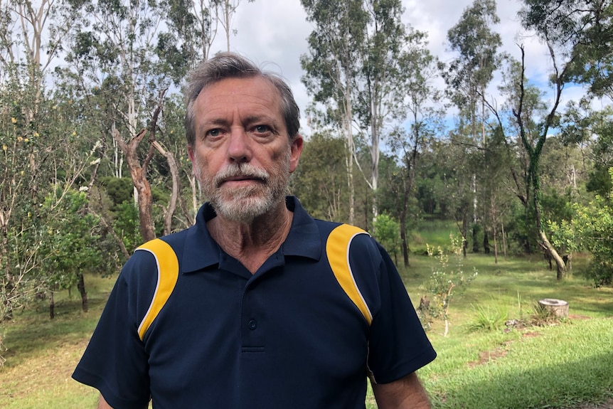 A man stands outside in a park.