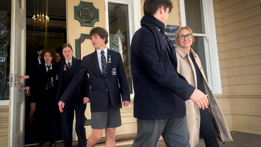 Emma Grant walking with students out the doors of the school.