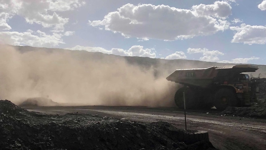 Dust is kicked up by heaving earth moving machinery at a mining site.