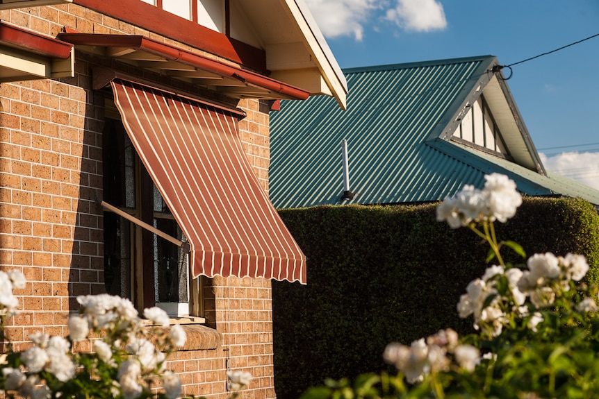 An adjustable awning shade blocking direct sunlight on a house window.
