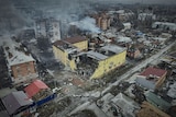 An aerial view of Bakhmut shows many damaged houses and smoke rises from some buildings.