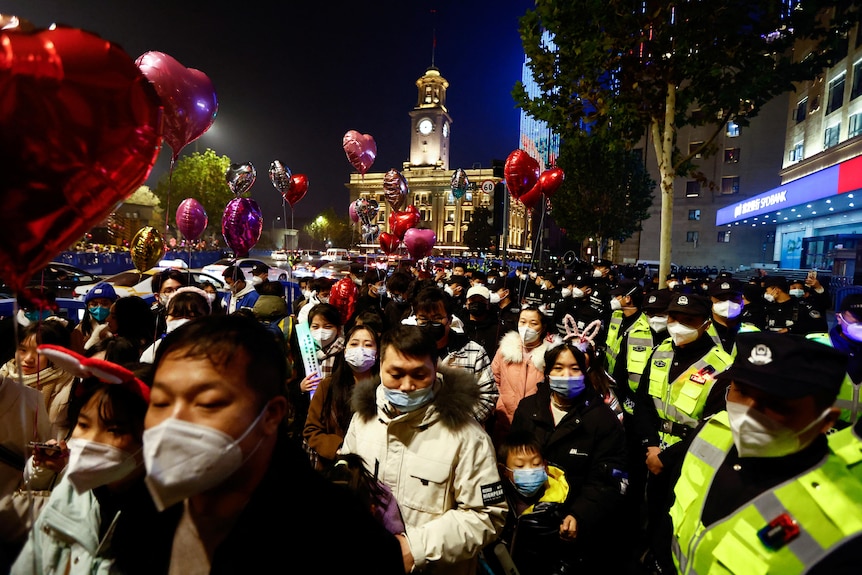 Police stand beside large crowd of New Year's Eve revellers in Wuhan.