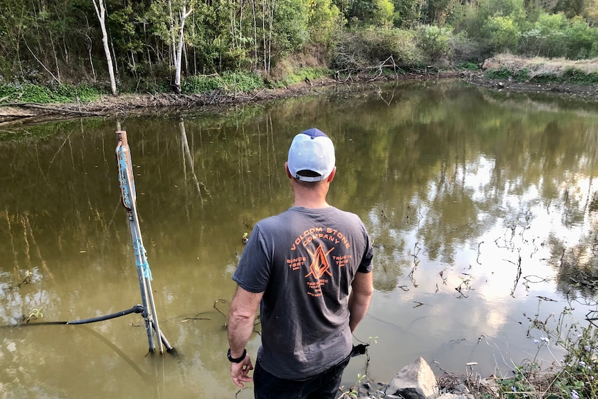 A man looks out over a dam.