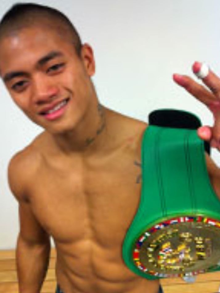 A man holds a green kickboxing championship belt