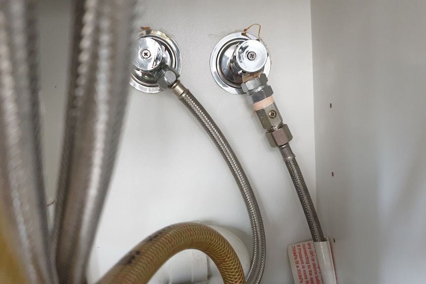 Two bendy metal pipes attached to back wall