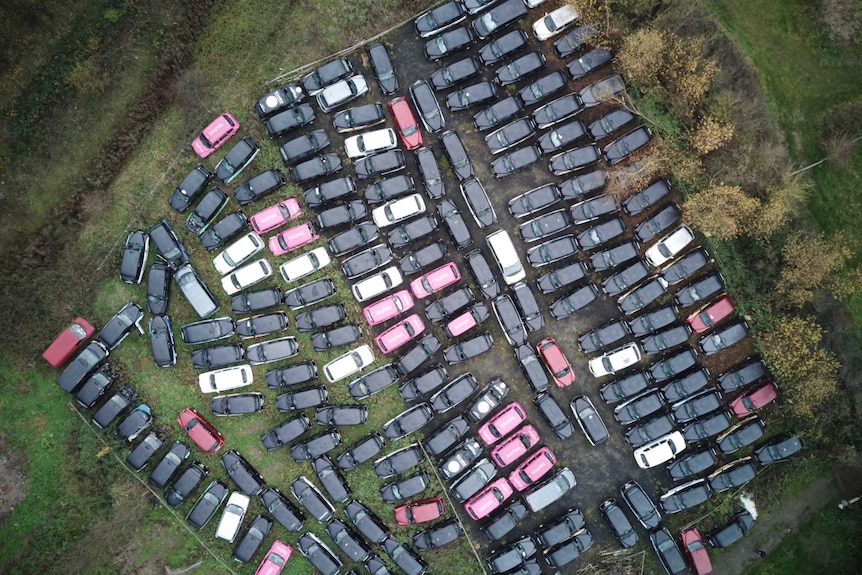 An aerial top-down view of a field of disused taxis outside of London.