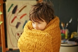 Six-year-old Monty von Nordheim of Yeerongpilly in Brisbane holds a blanket close around his body.