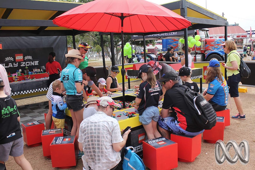 Children and their parents play with Lego under a red umbrella at the Townsville 400