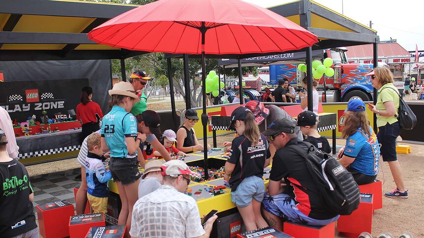 Children and their parents play with Lego under a red umbrella at the Townsville 400