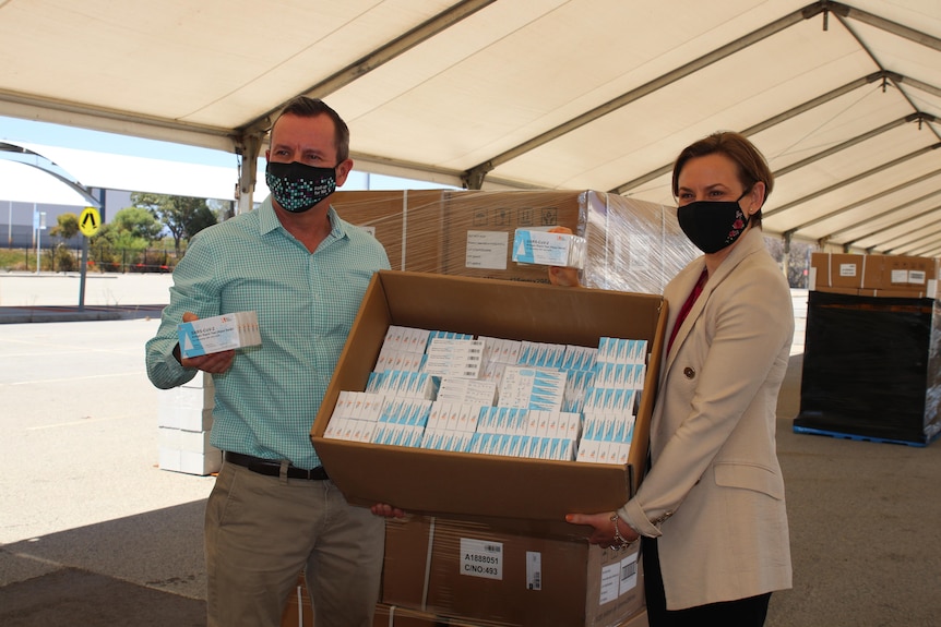 Mark McGowan and Amber-Jade Sanderson holding a box of RATs