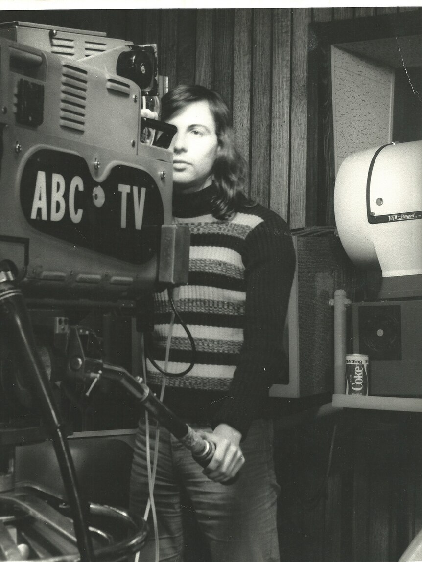 Black and white photo of Julie before transitioning operating a camera with ABC TV on side.