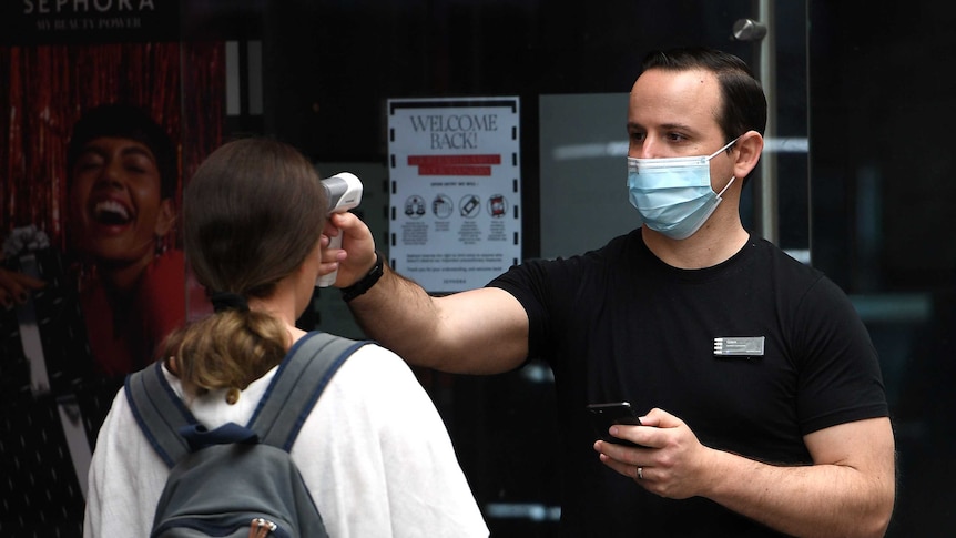 Shoppers are seen being temperature checked on entry to a store in Sydney.