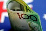 An Australian $100  note is seen with Australian flag behind