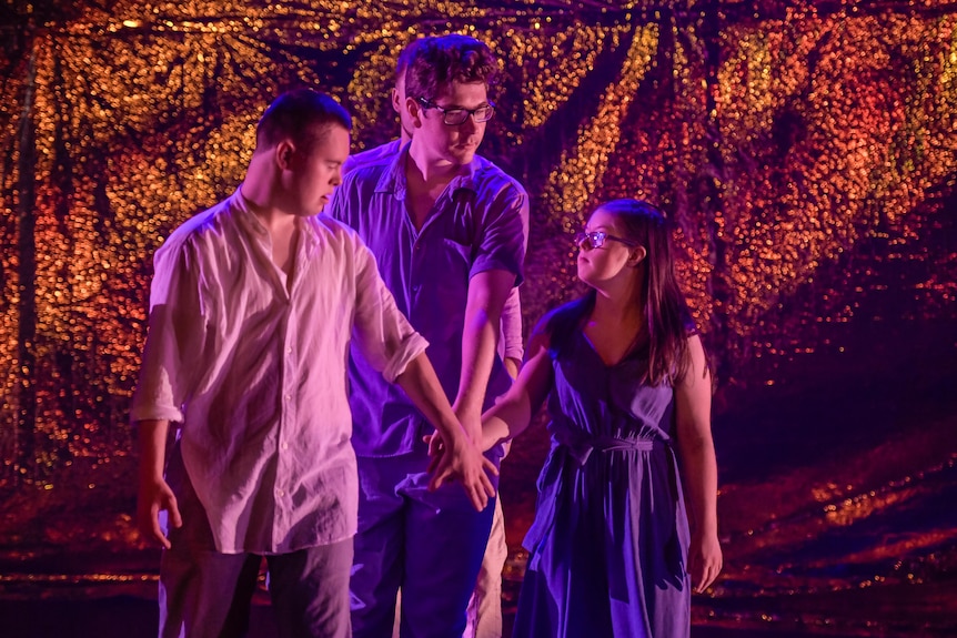 A brunette white man with down syndrome, a brunette white man and a brunette white woman with down syndrome perform onstage