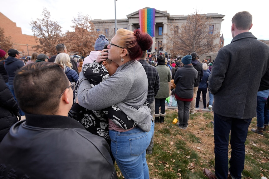 Onlookers embrace after a pride flag was raised.