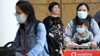People wearing face masks arrive at an airport