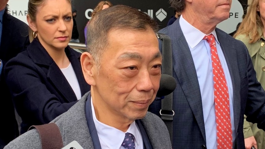 A man walking along the street surrounded by people.