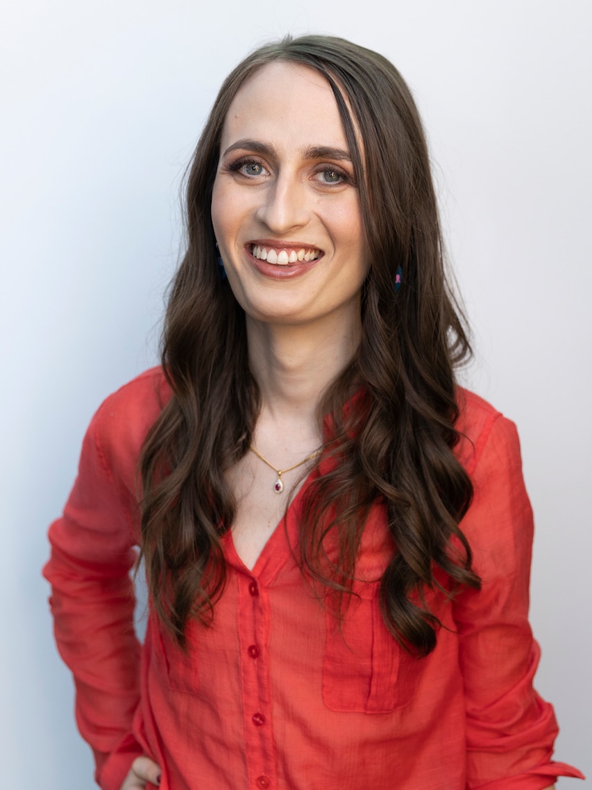 A woman with long brown hair smiles.