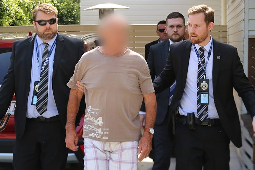 A man being led by three police officers