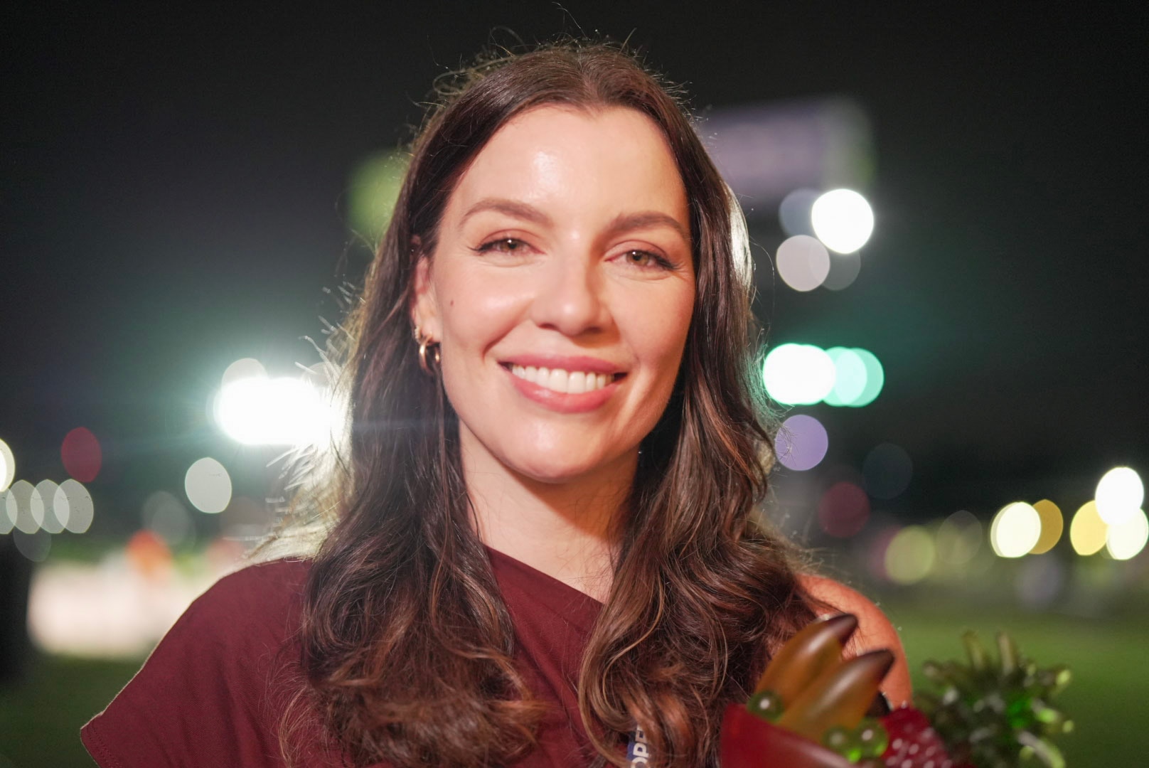 A woman with brown coloured, shoulder length hair in a red shirt.