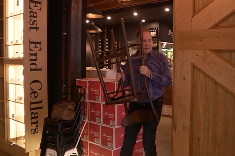 A man walks holding a stool upside down