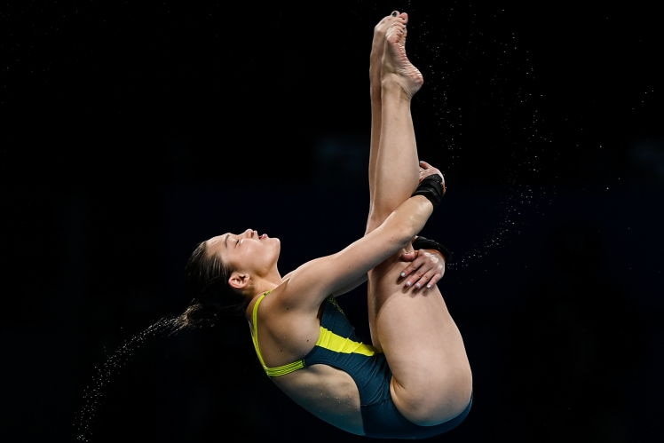 Australian diver Melissa Wu holds a pike position mid-air during a 10-metre platform dive. Water is flicking off her hair.