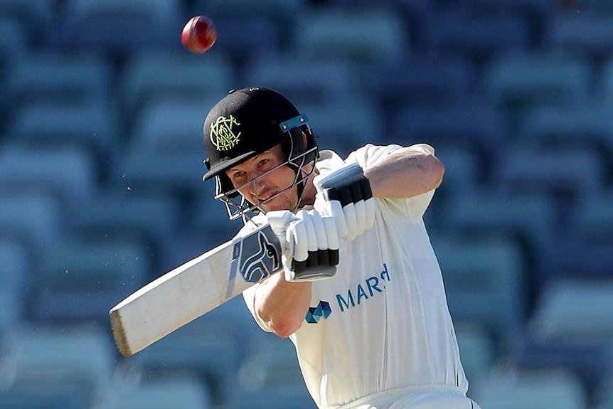 Cameron Bancroft hits a shot while batting for WA with the cricket ball ballooning up into the air above his head.