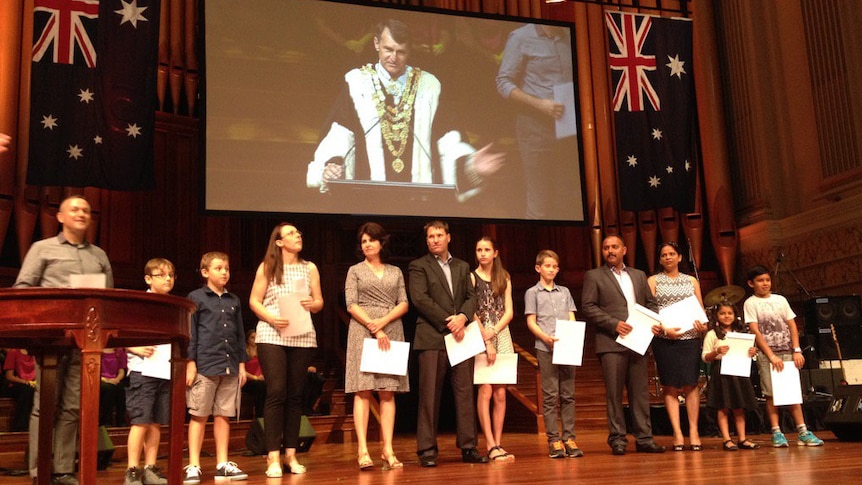New Australians holding their proof of citizenship at a ceremony in Brisbane.