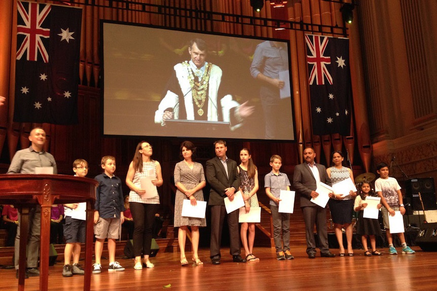 New Australians holding their proof of citizenship at a ceremony in Brisbane.