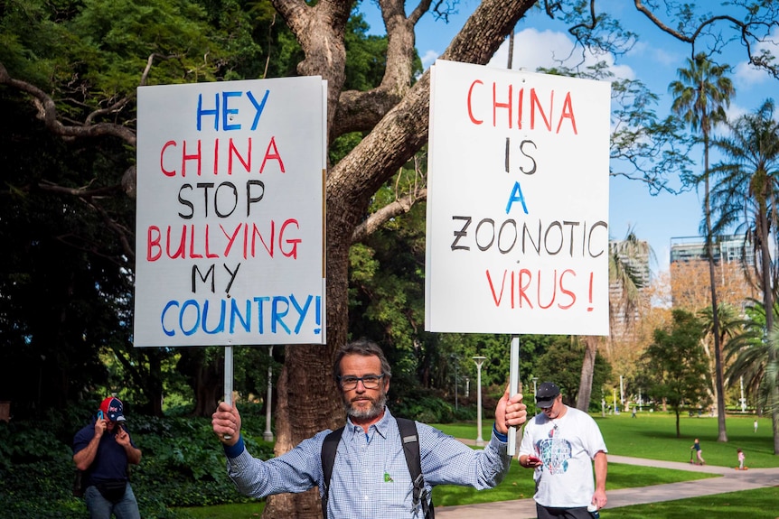 Nick Folkes carries signs in Hyde Park, Sydney one reads: 'China is a zoonotic virus!'