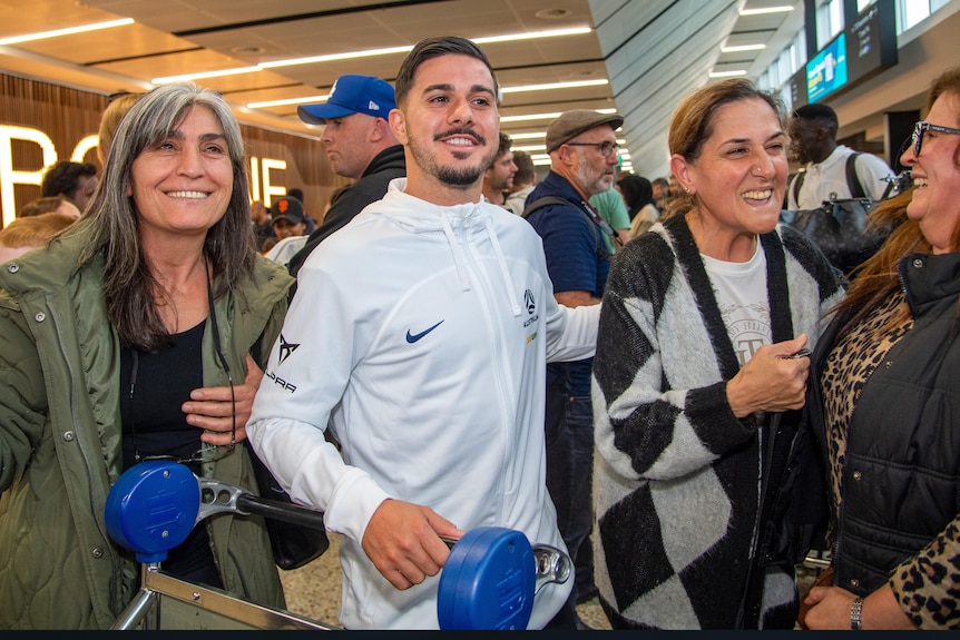 Marco Tilio entouré de deux supporters à l'aéroport de Melbourne.