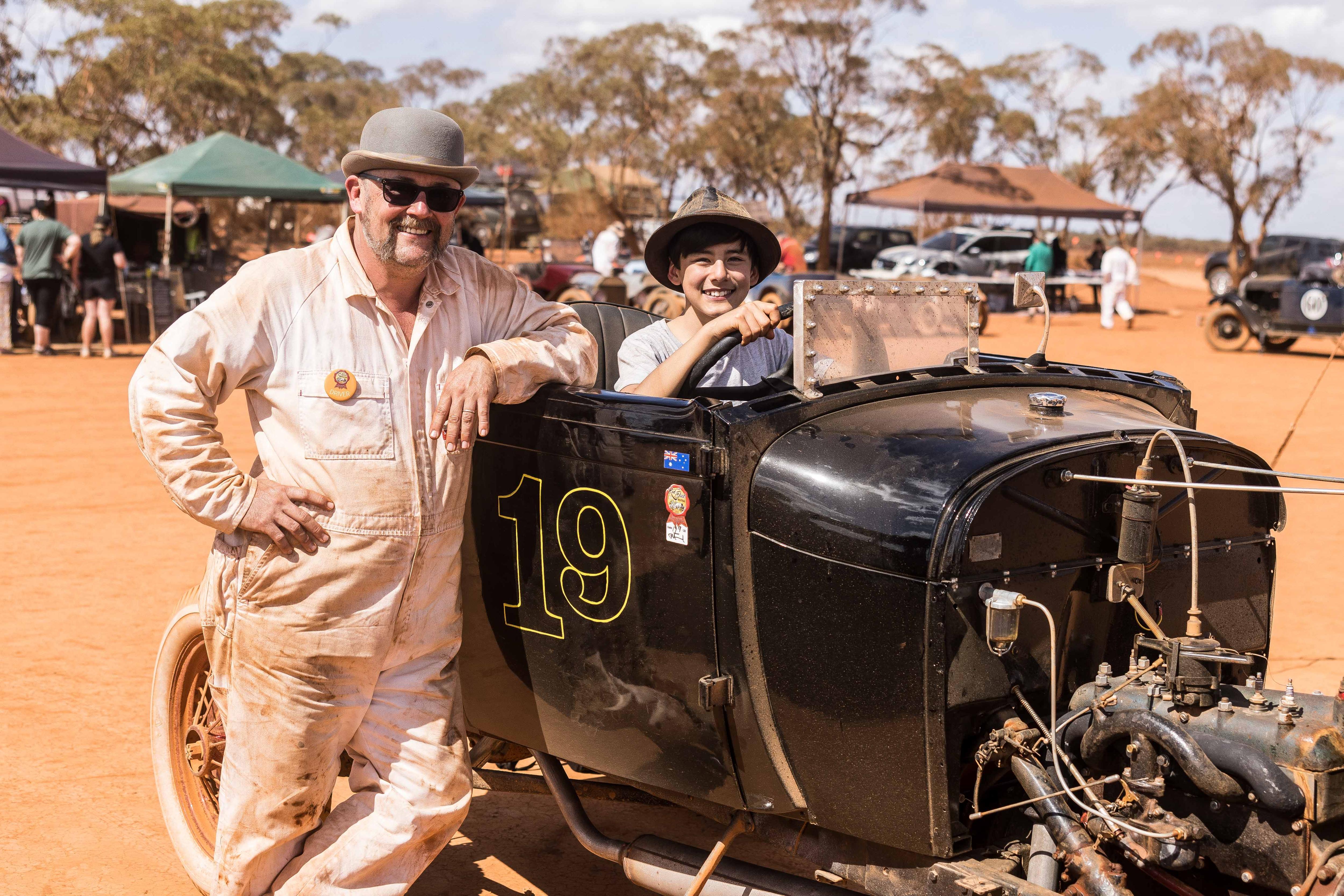 A father and son at a vintage car event.  