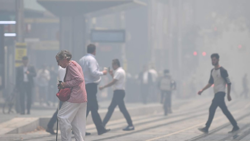 People cross George Street as smoke blankets Sydney