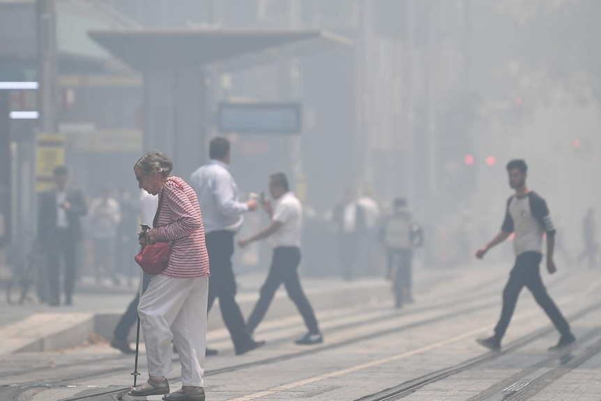 People cross George Street as smoke blankets Sydney